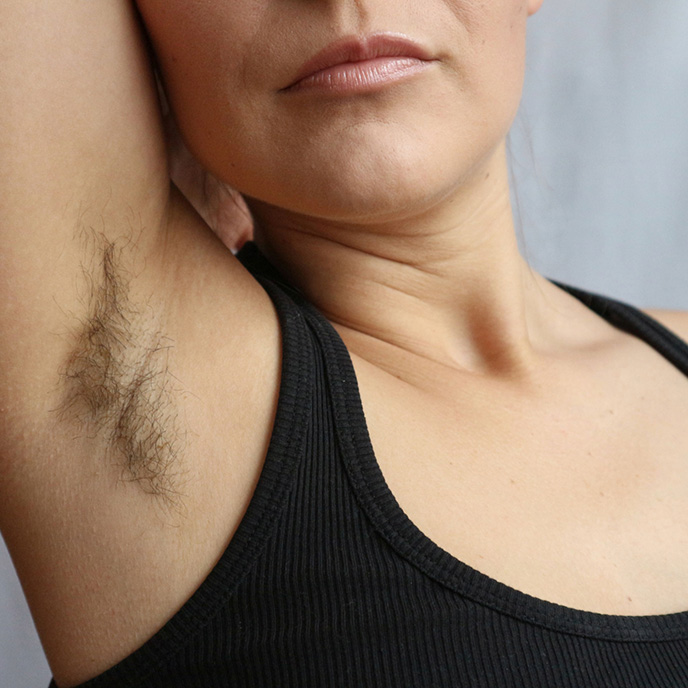 Female unshaved armpit with thick hair.